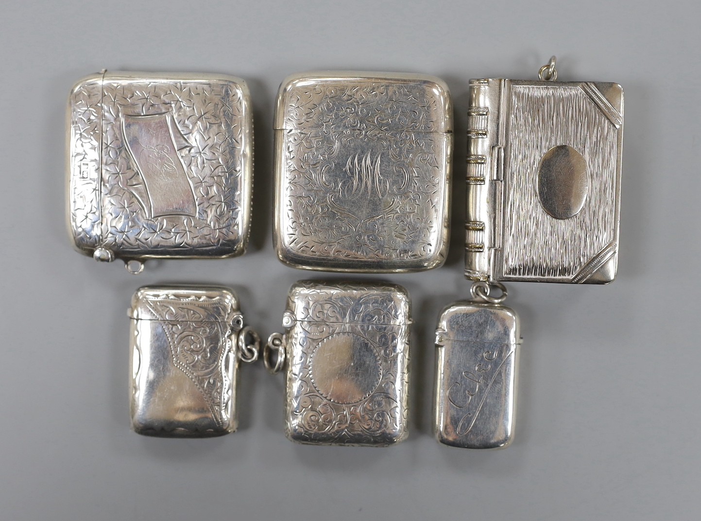 Five assorted Victorian and later silver vesta cases, largest, 488 and a plated novelty combination vesta/stamp case, modelled as a book.